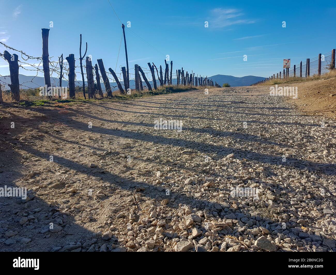 wide dirt road bordered by a fence Stock Photo