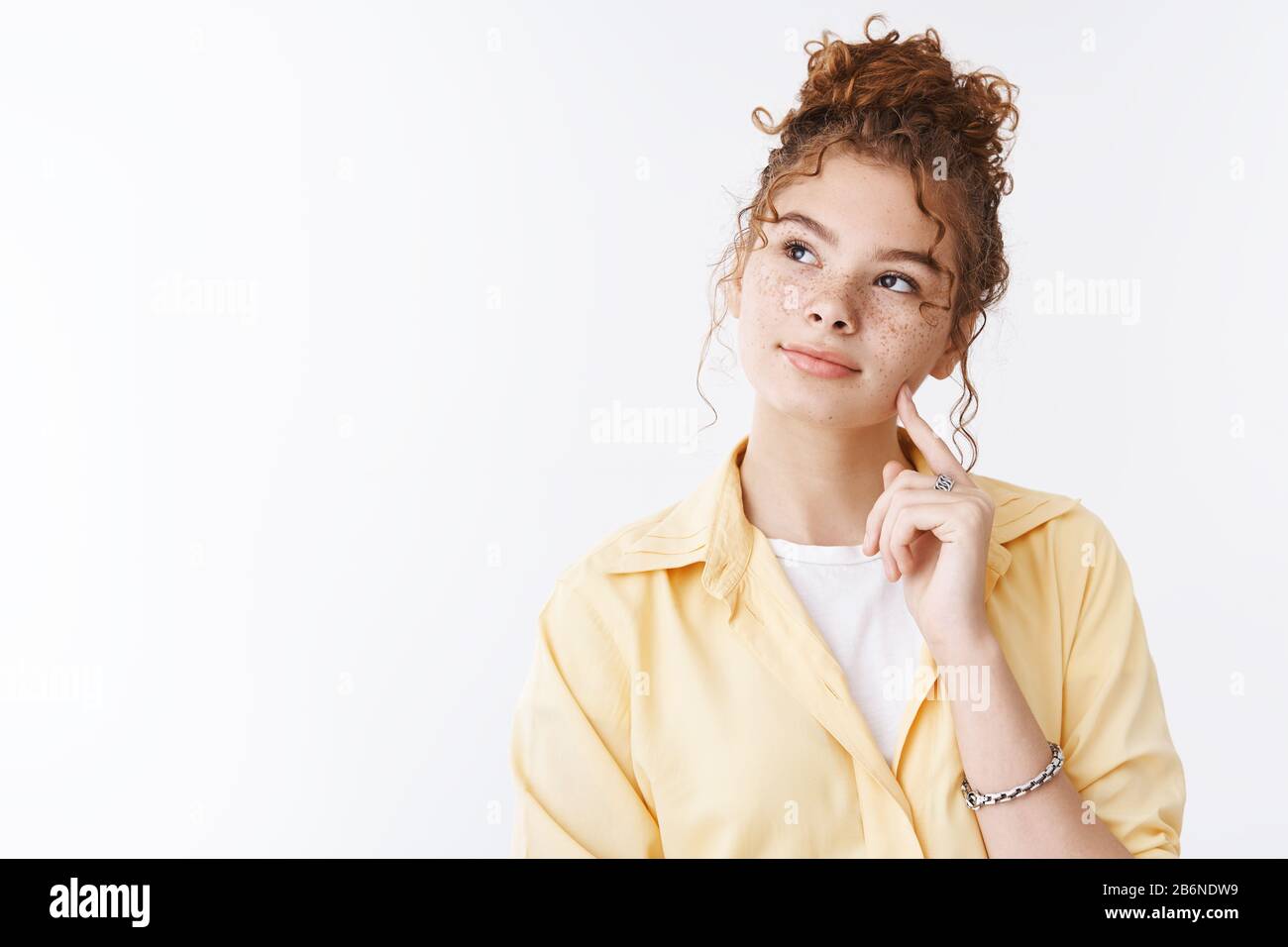 Dreamy thoughtful attractive cute feminine redhead girl freckles messy bun haircut tilting head
