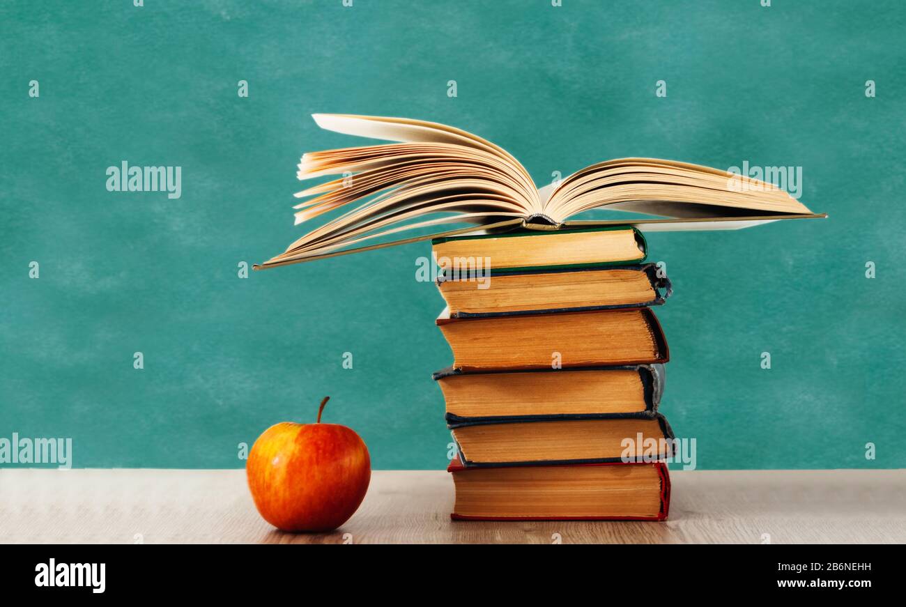 Back to school, pile of books and red apple with empty school board ...