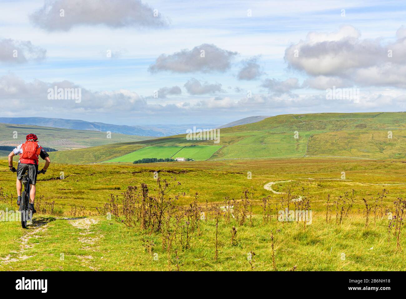 Cyclist (on e-bike) descending towards Newby Head on the Pennine Bridleway in the Yorkshire Dales Stock Photo