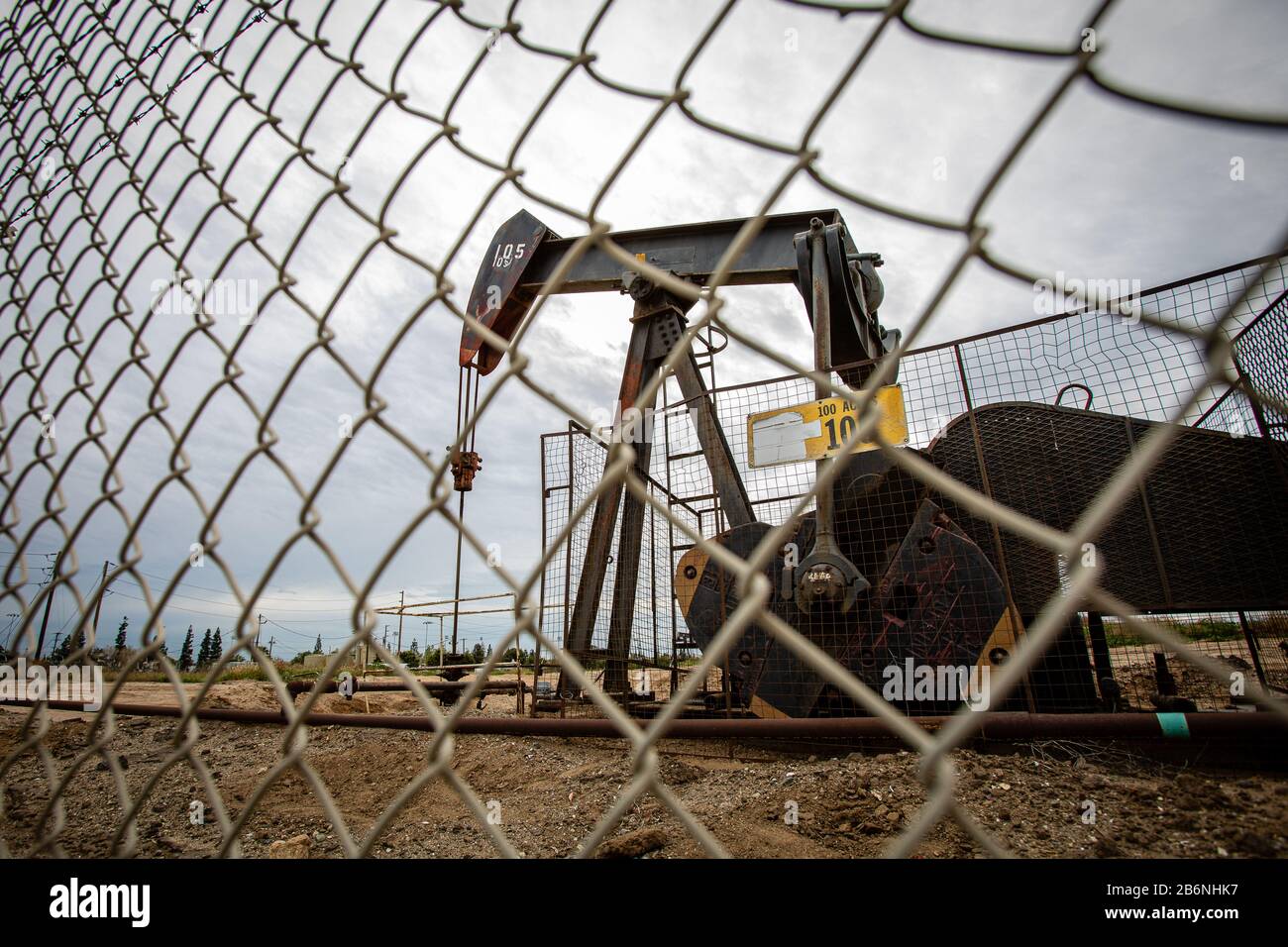 Oil Pump in Cloudy Rough Weather with Chain Link Fence Stock Photo