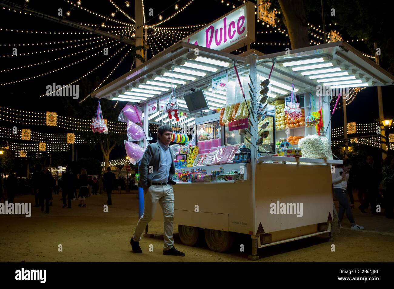 Night shot of a man walking close to a sweeties kiosk at the Feria de Abril enclosure, Seville, Spain Stock Photo