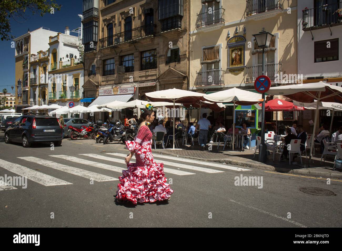 Girl wearing a Sevillian costume at the Altozano Square crosswalk in Triana District, Seville, Spain Stock Photo