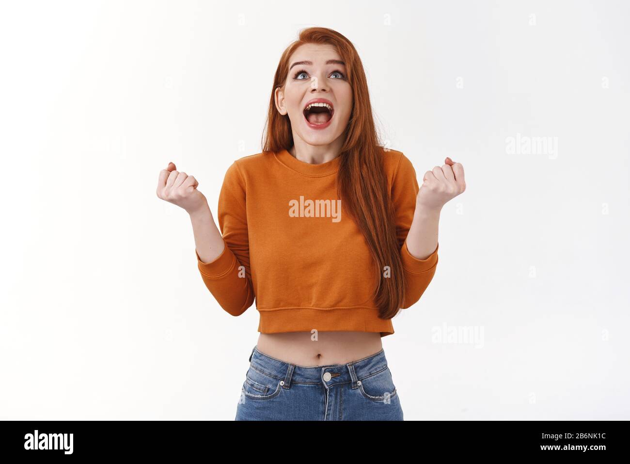 Achievement, happiness and win concept. Excited good-looking redhead woman winning prize, screaming from amazement and overjoy, clench fists look up Stock Photo