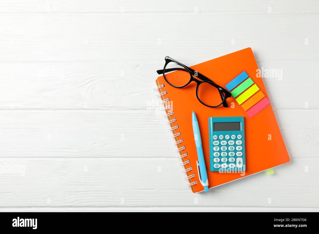 Copybook, glasses, calculator, pen and stickers on wooden background, space for text Stock Photo