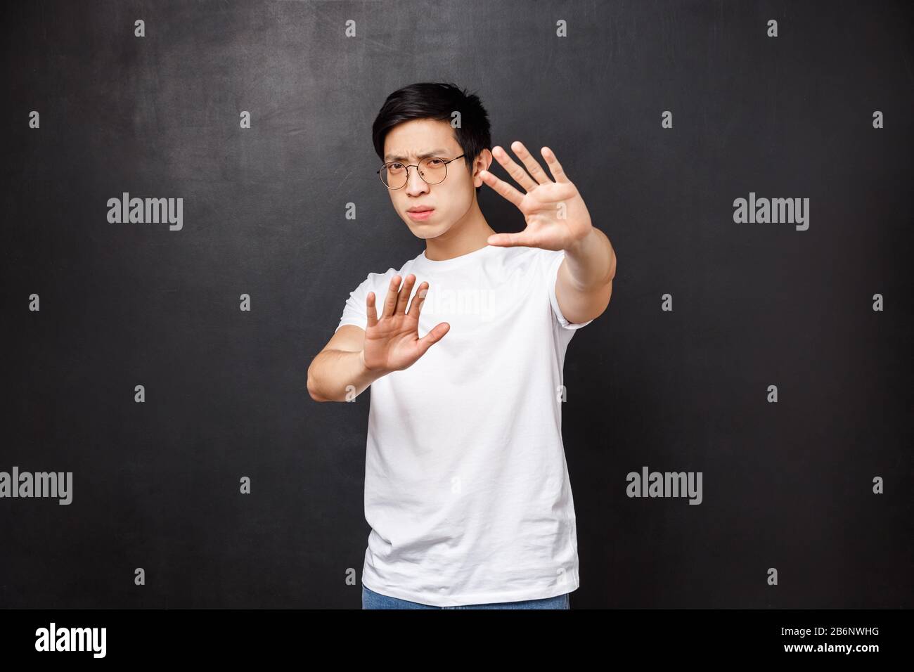 Serious-looking annoyed and displeased asian guy telling stop it, cover face with hands as if defending himself from glimmering light, squinting Stock Photo