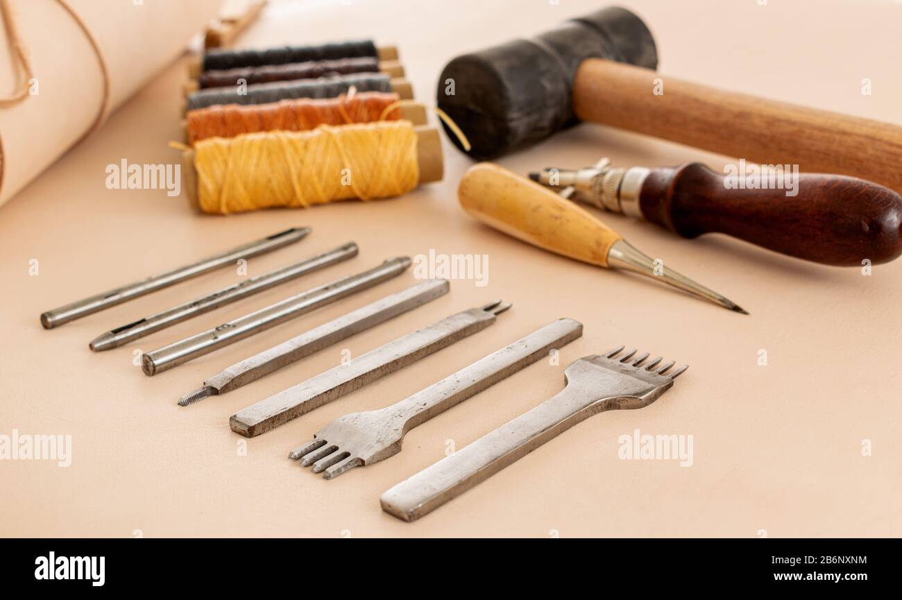 Leather working tools and rolled up hide organized Stock Photo
