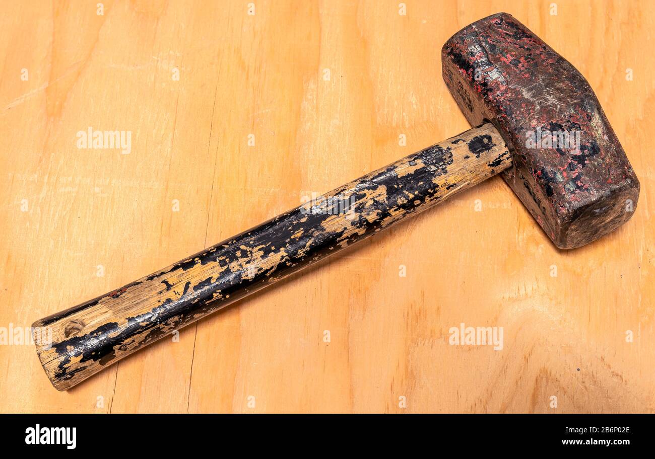 A heavily used and weathered mallet hammer on a stained wood background Stock Photo