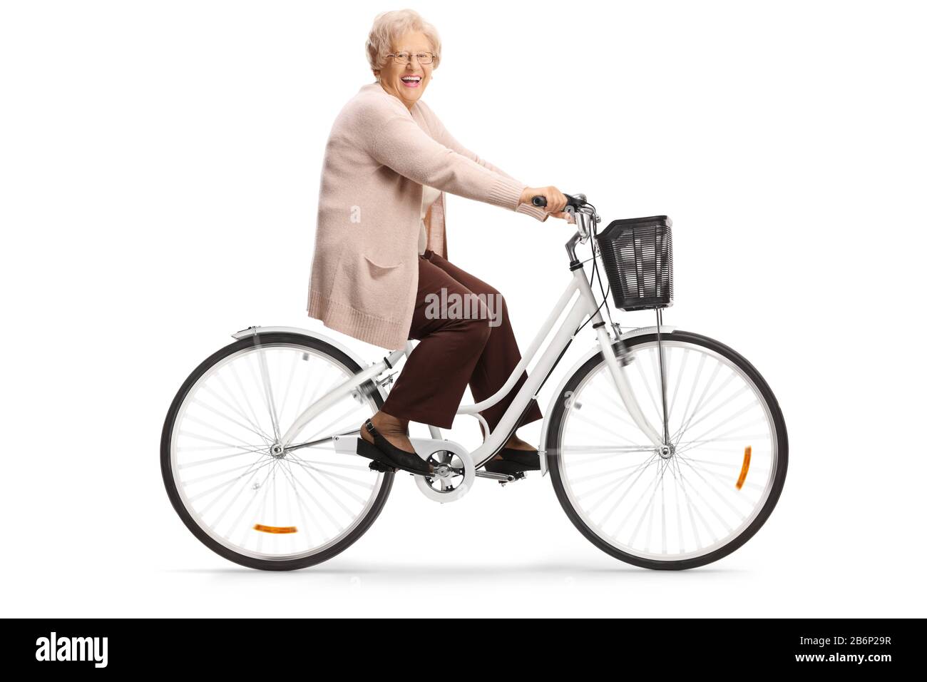 Elderly lady riding a bicycle and smiling at camera isolated on white background Stock Photo