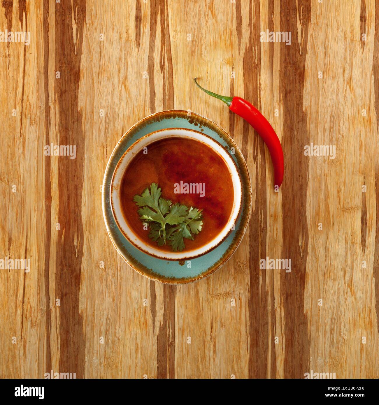 moroccan food, tomatoe soup dish decorated with parsley, on a plate with red hot chili pepper, on a wooden table and copy space for text Stock Photo
