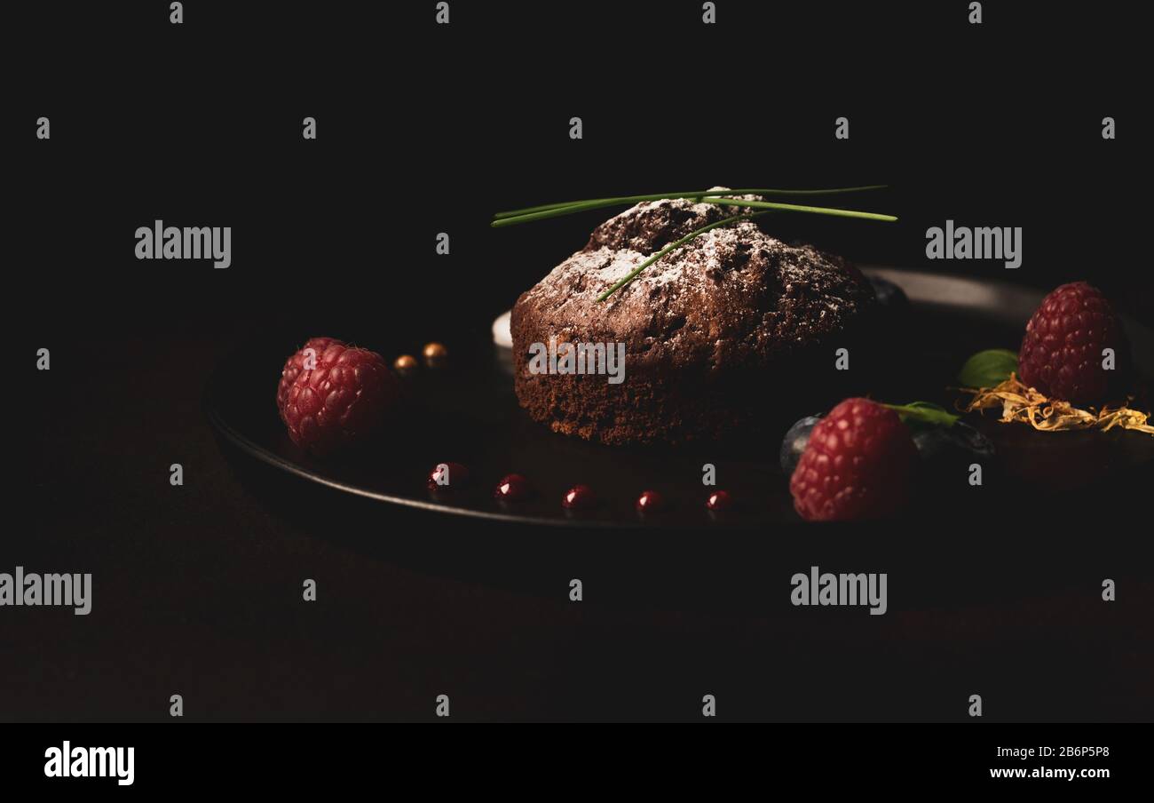 Chocolate muffins with raspberries and blueberries on a black plate with backlight, Food photo with bright colors Stock Photo