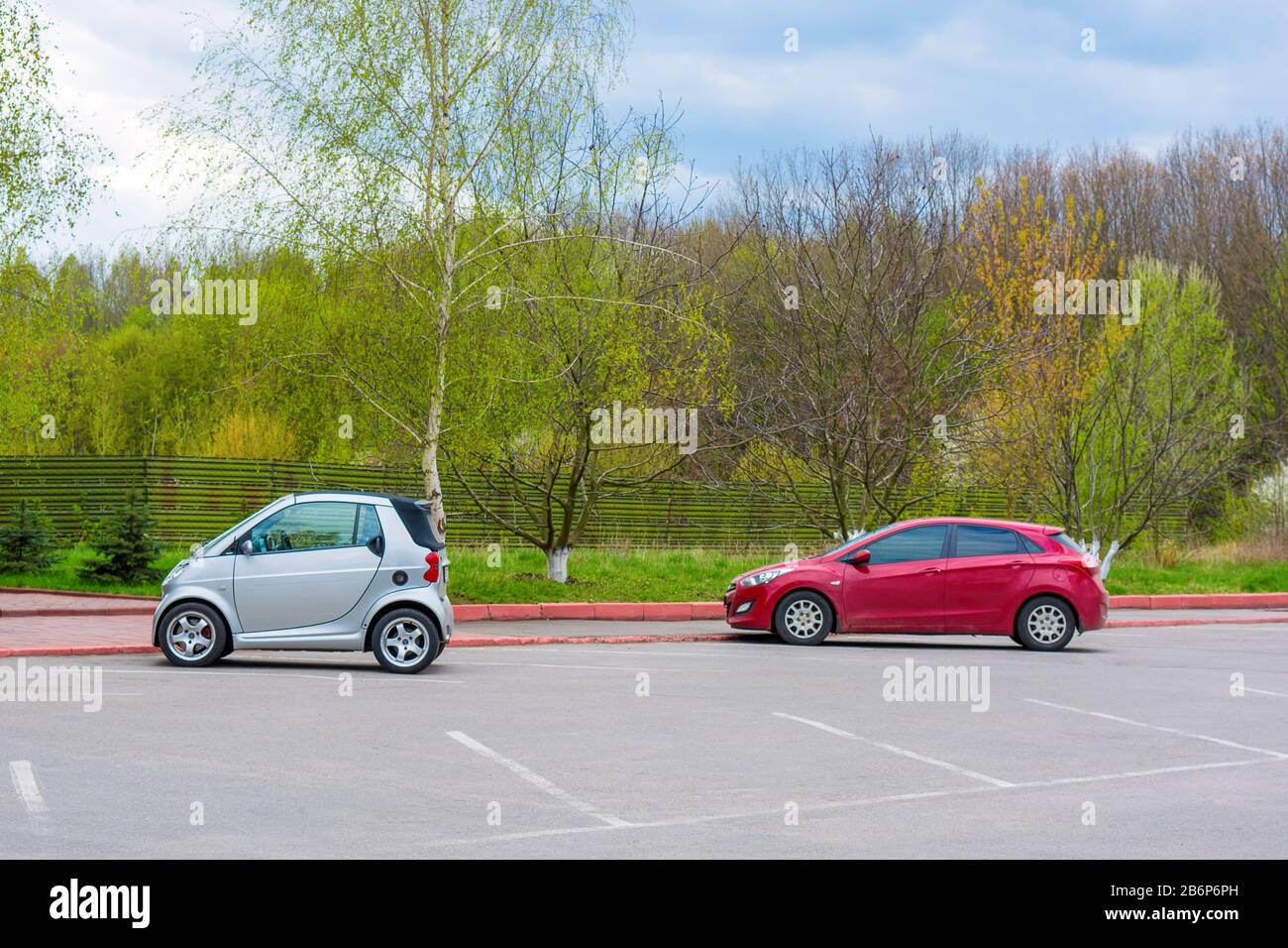 Photo of car parking with small white and red cars near the park Stock Photo