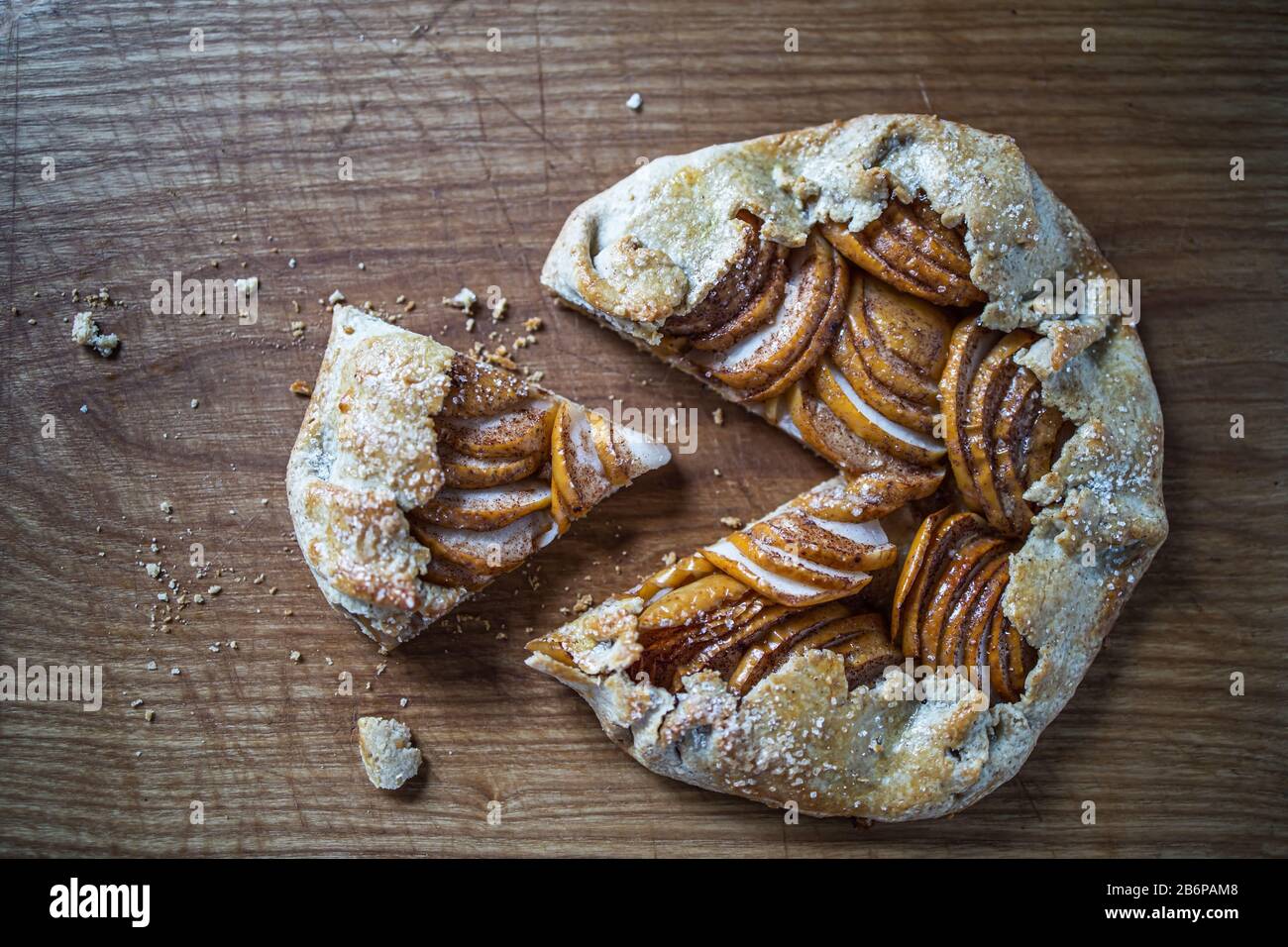 Apple galette - pie sliced into pieces on a wooden dark background. Copy space, flat lay. Stock Photo