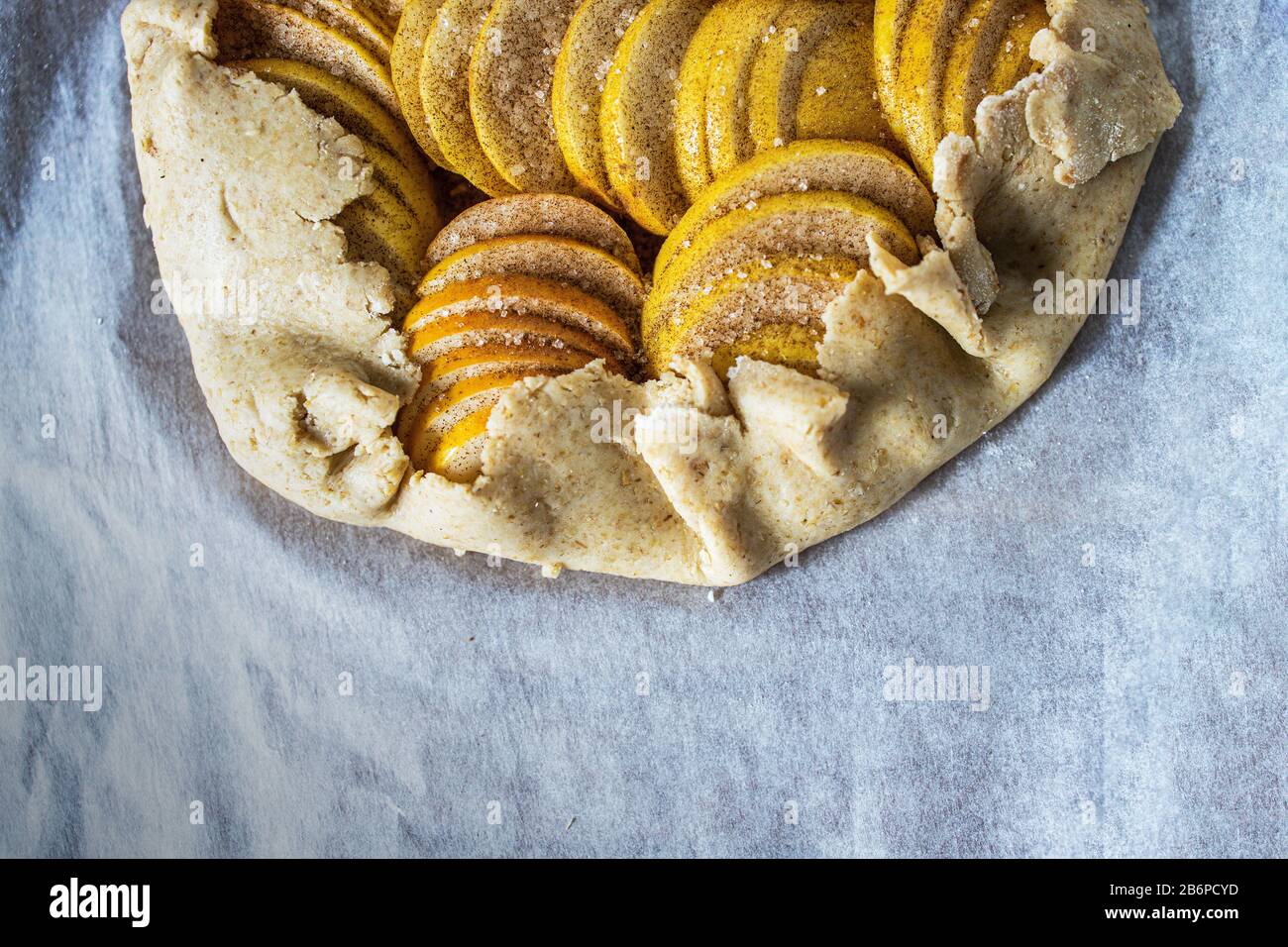 Raw apple galette - pie on white baking parchment. Copy space, flat lay. Stock Photo