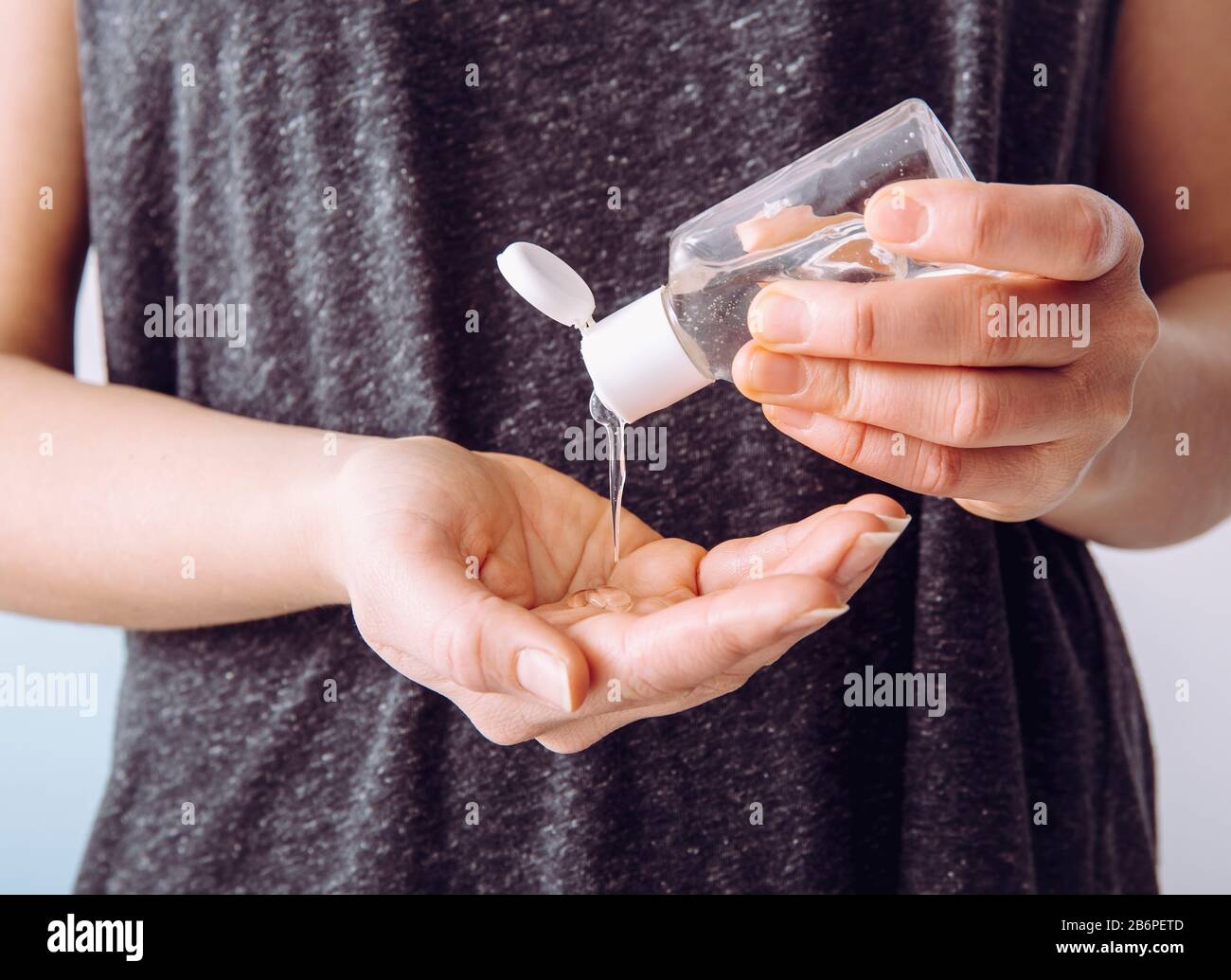 Close up view of woman person using small portable antibacterial hand sanitizer on hands. Stock Photo