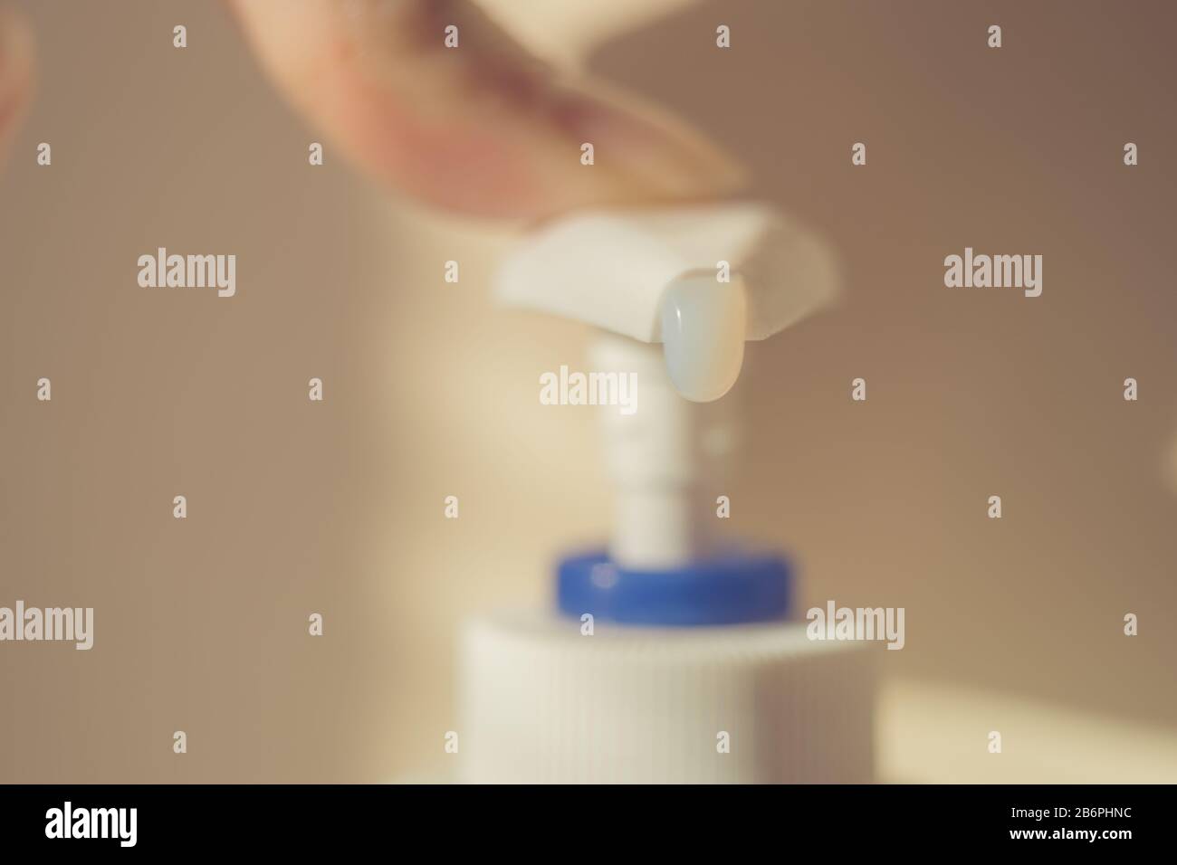Female finger touch on a liquid soap dispenser. White gel begins to fall out of the bottle. Stock Photo