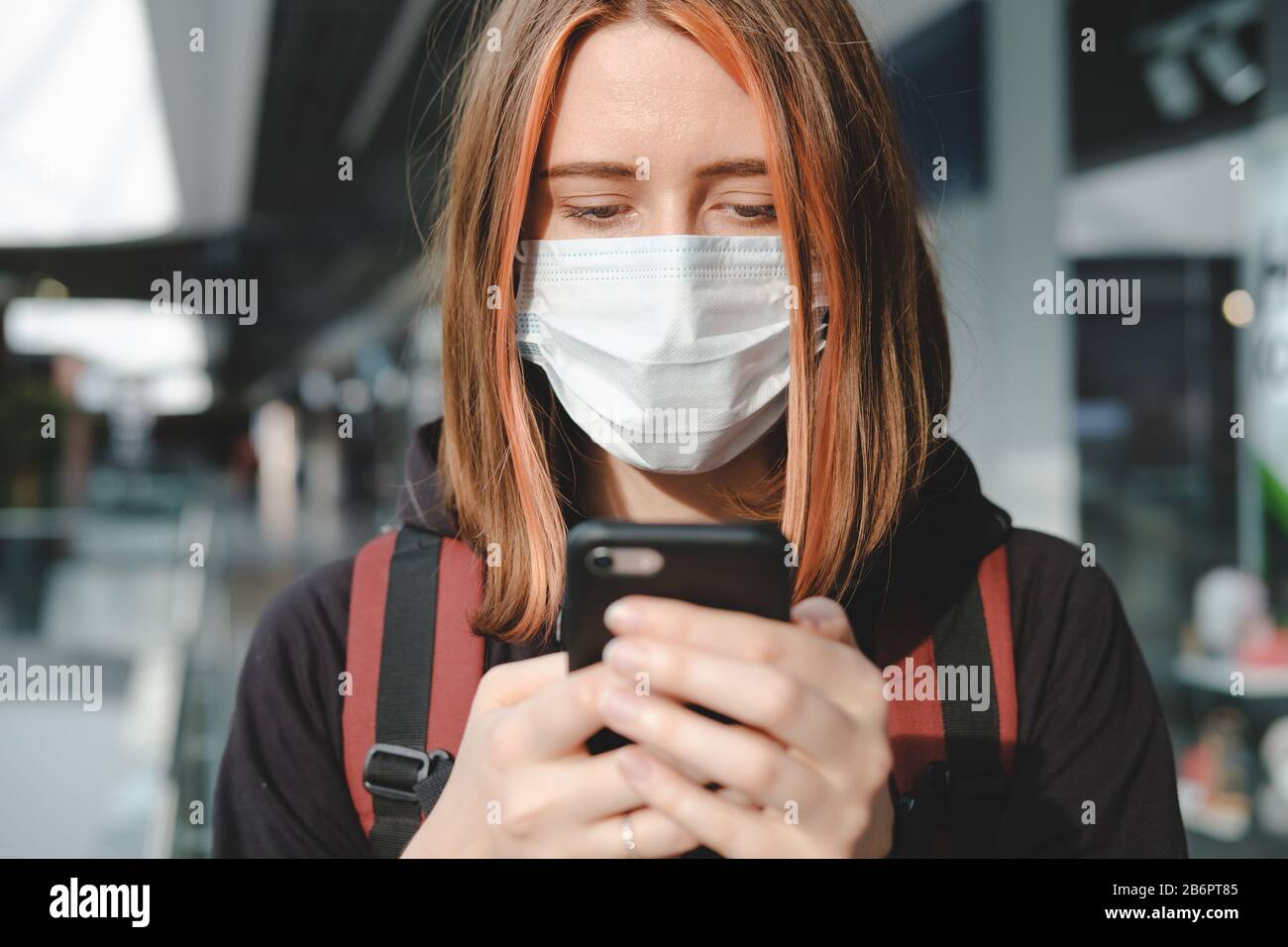 Woman in protective face mask using the phone at a public place. Coronavirus, COVID-19 spread prevention concept, responsible social behaviour of a ci Stock Photo