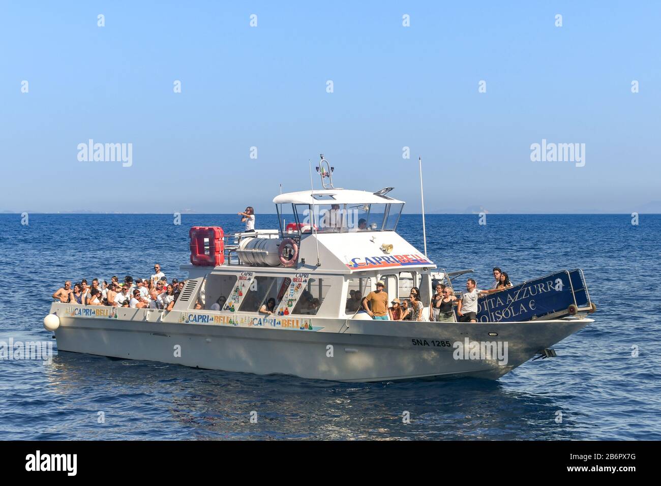 ISLE OF CAPRI, ITALY - AUGUST 2019: Group of people on board a motor boat on a tourist excursion around the Isle of Capri. Stock Photo