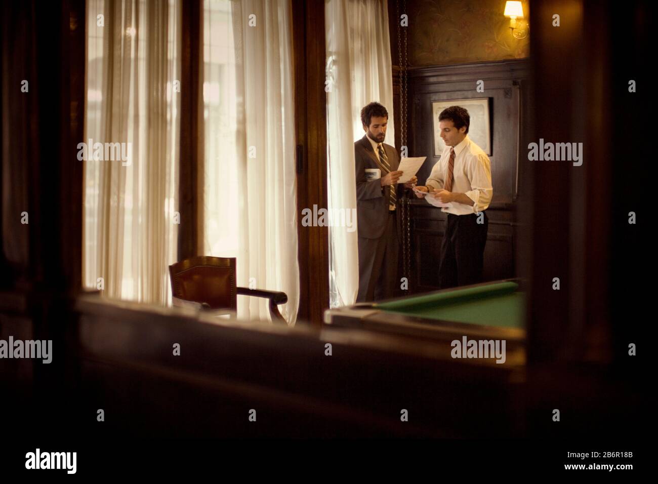 View of two businessmen through mirror discussing work. Stock Photo