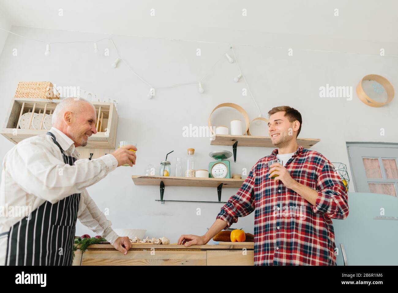 Young man and his father cooking in kitchen Stock Photo