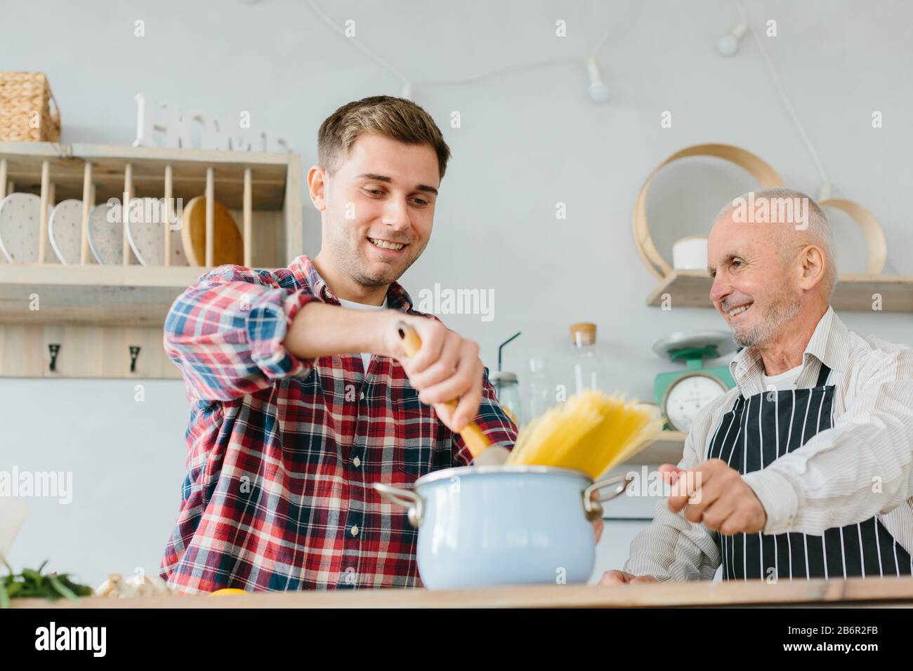 Young man and his father cooking in kitchen Stock Photo