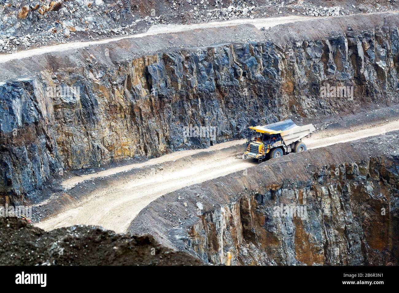 A Komatsu dump truck traveling down into Coldstones Quarry to be refilled with rock to be transported to the crushing machine at the top of the quarry Stock Photo