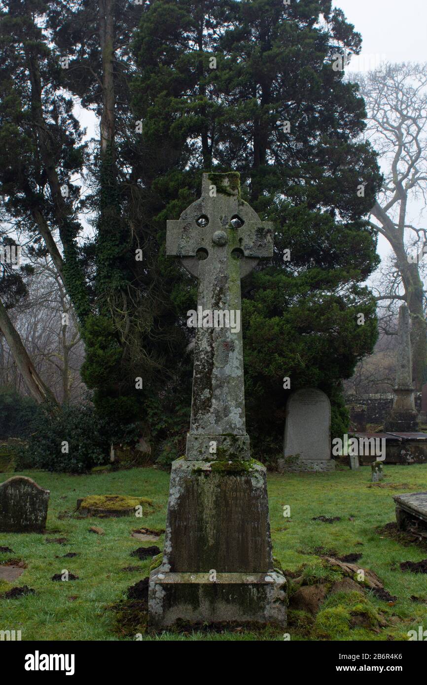 A grave stones and a celtic cross ion a misty morning in the Scottish Hihglands Stock Photo
