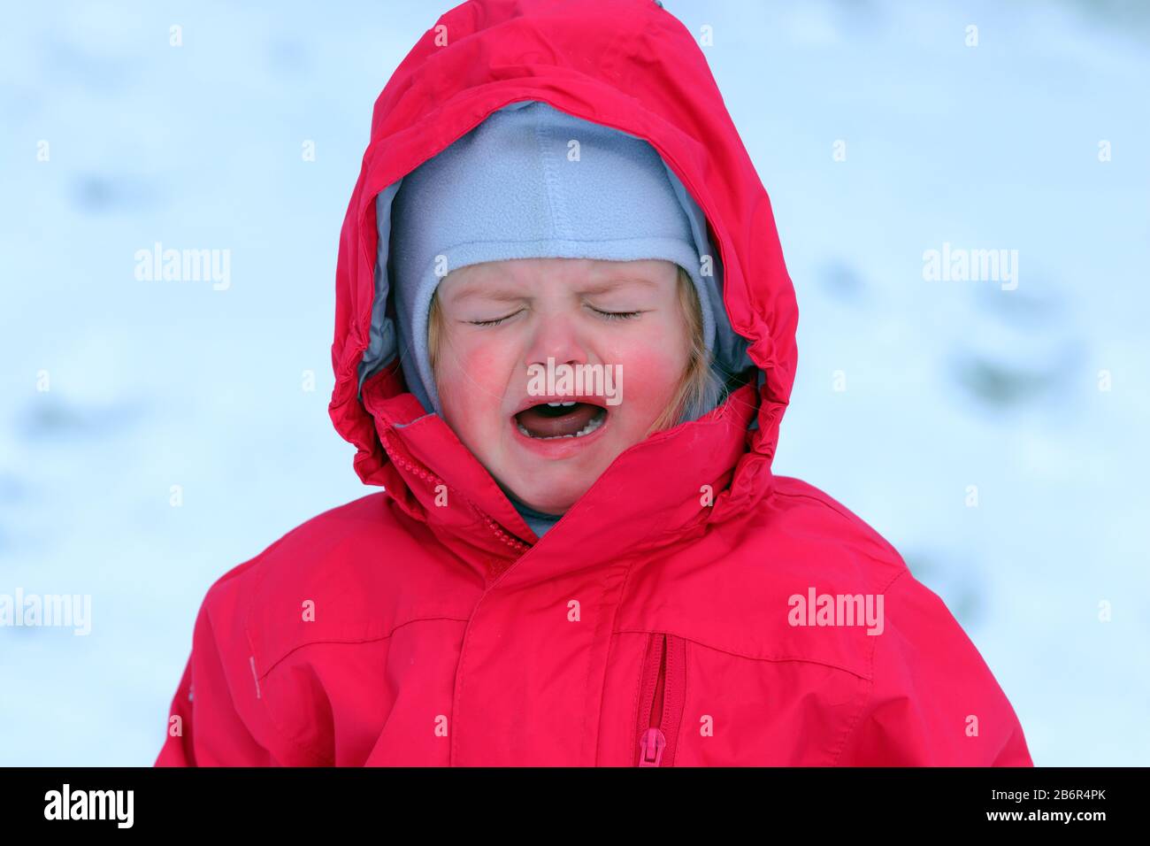 A little girl crying in the snow because it's too cold for her Stock