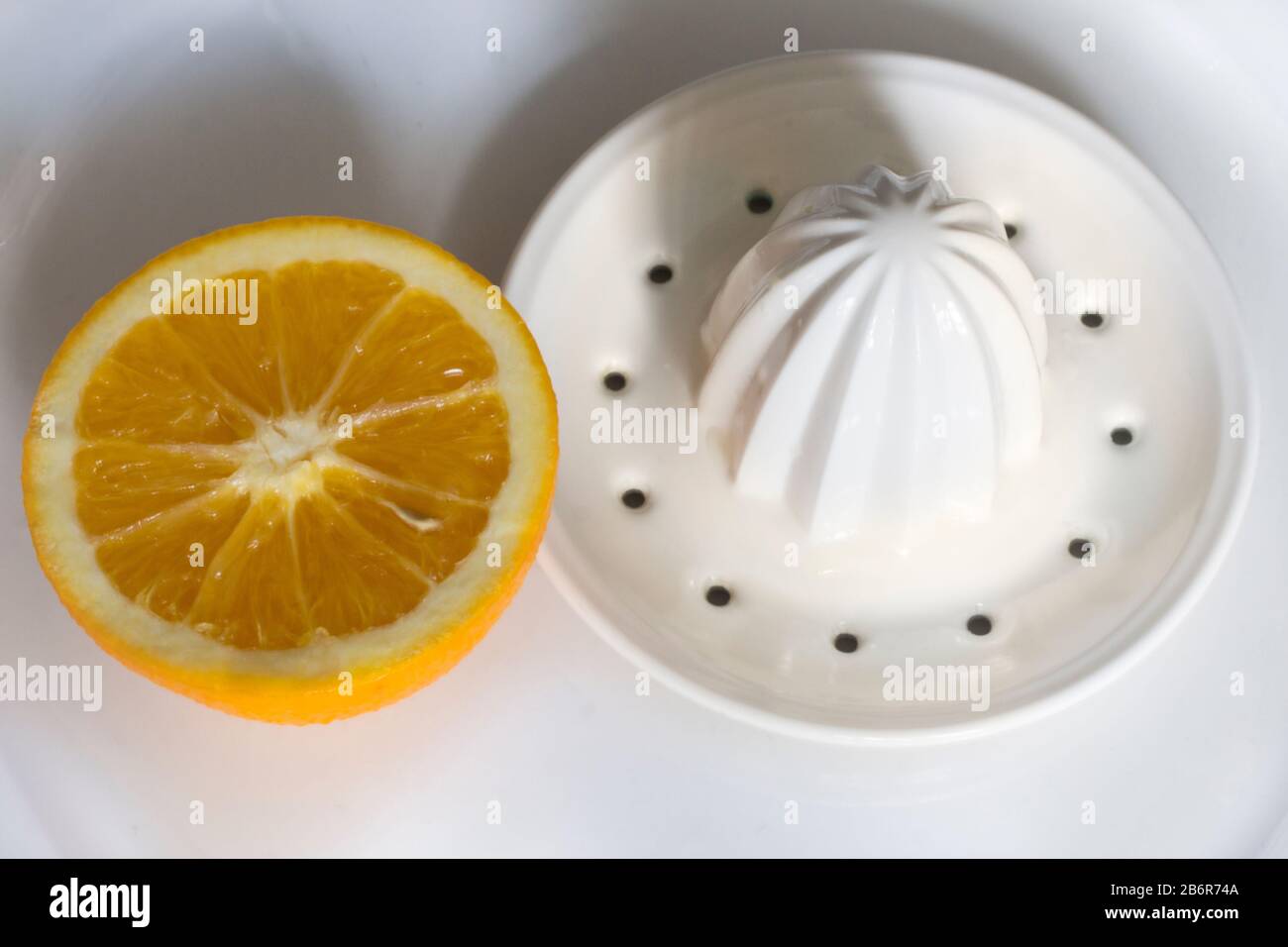 A orange and white ceramic citrus hand press on a plate. Stock Photo