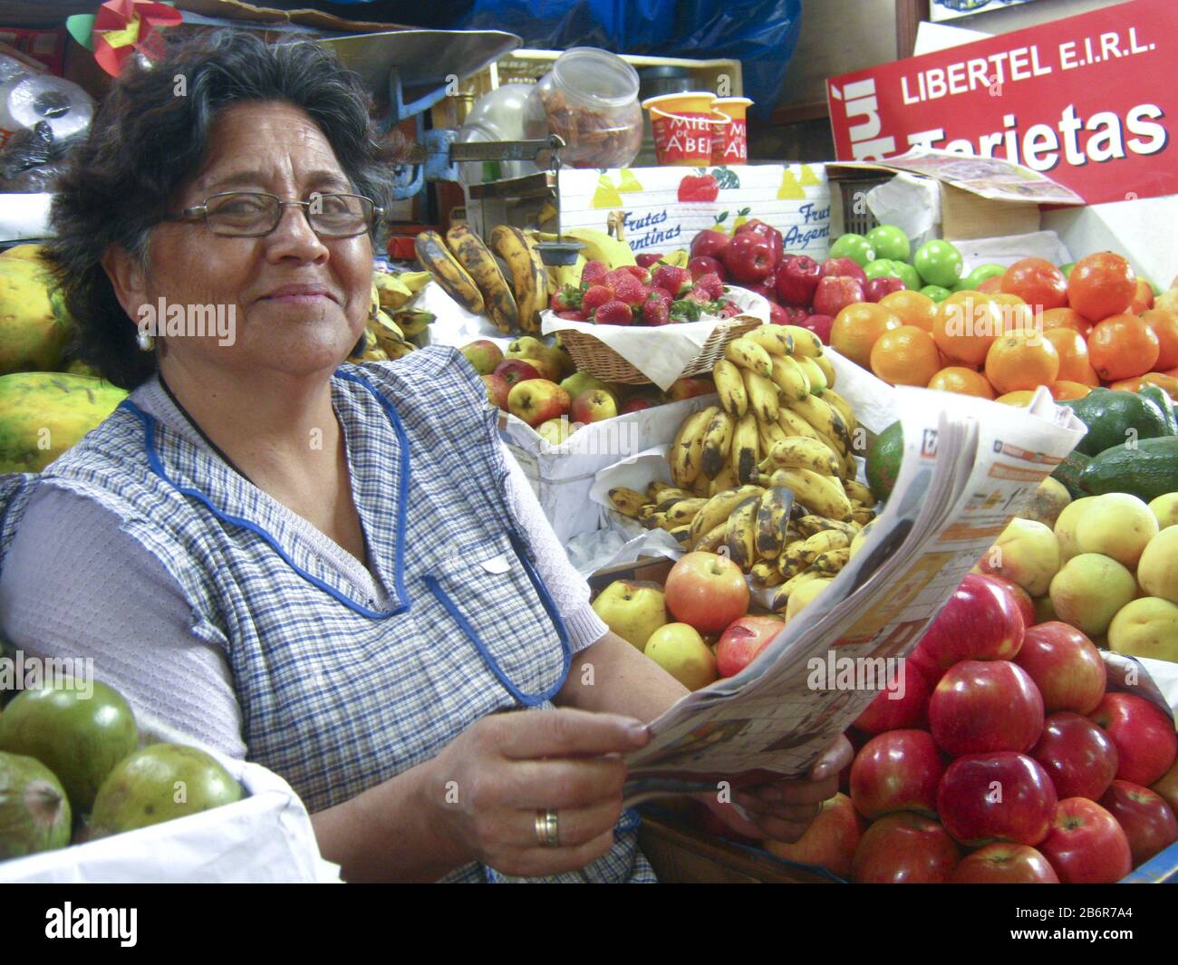 Cajamarca, Peru. Peruvian sales woman surrounded by fruit, reading a news paper in her fruit stall in the city market. March 2010 Stock Photo