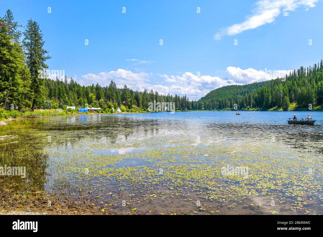 Two people fish from a small rowboat on Granite Lake with rural