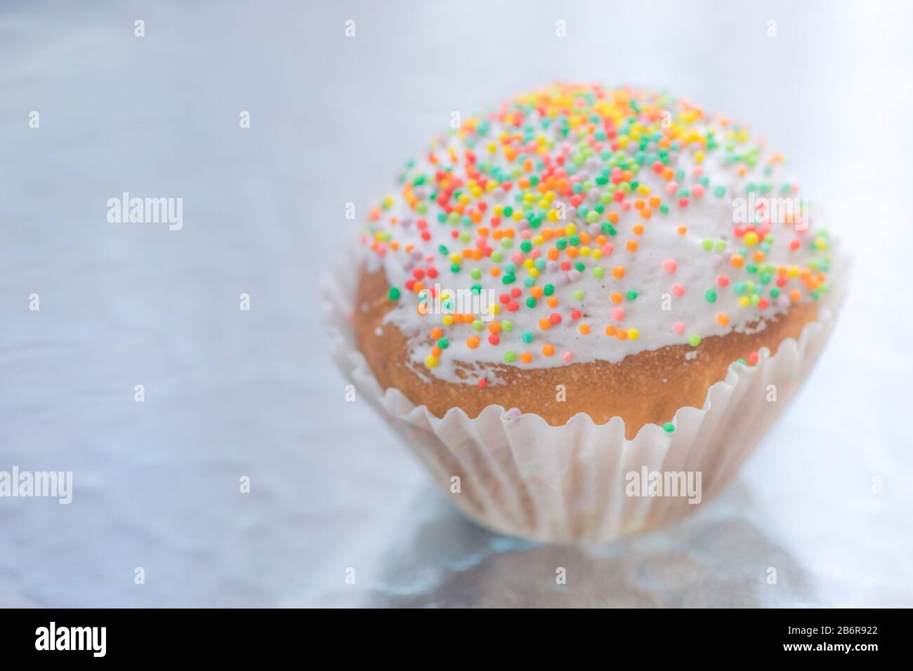 Easter cupcake wrapped in white paper on te table. Stock Photo