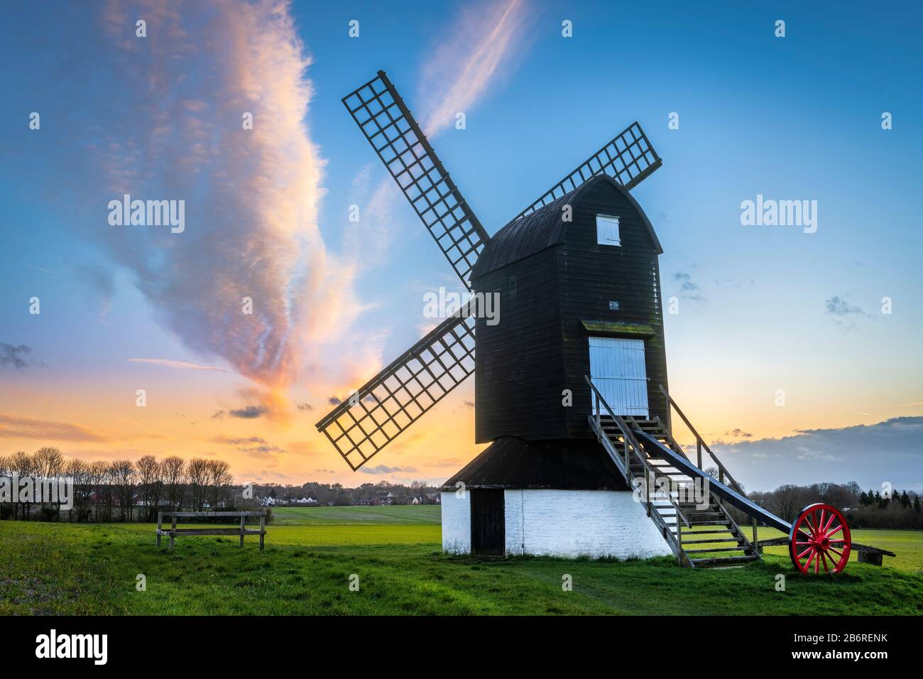 After a dry day with intermittent sunshine and a strong breeze in Ivinghoe, Buckinghamshire, the sun sets behind the famous Pitstone Windmill on the R Stock Photo