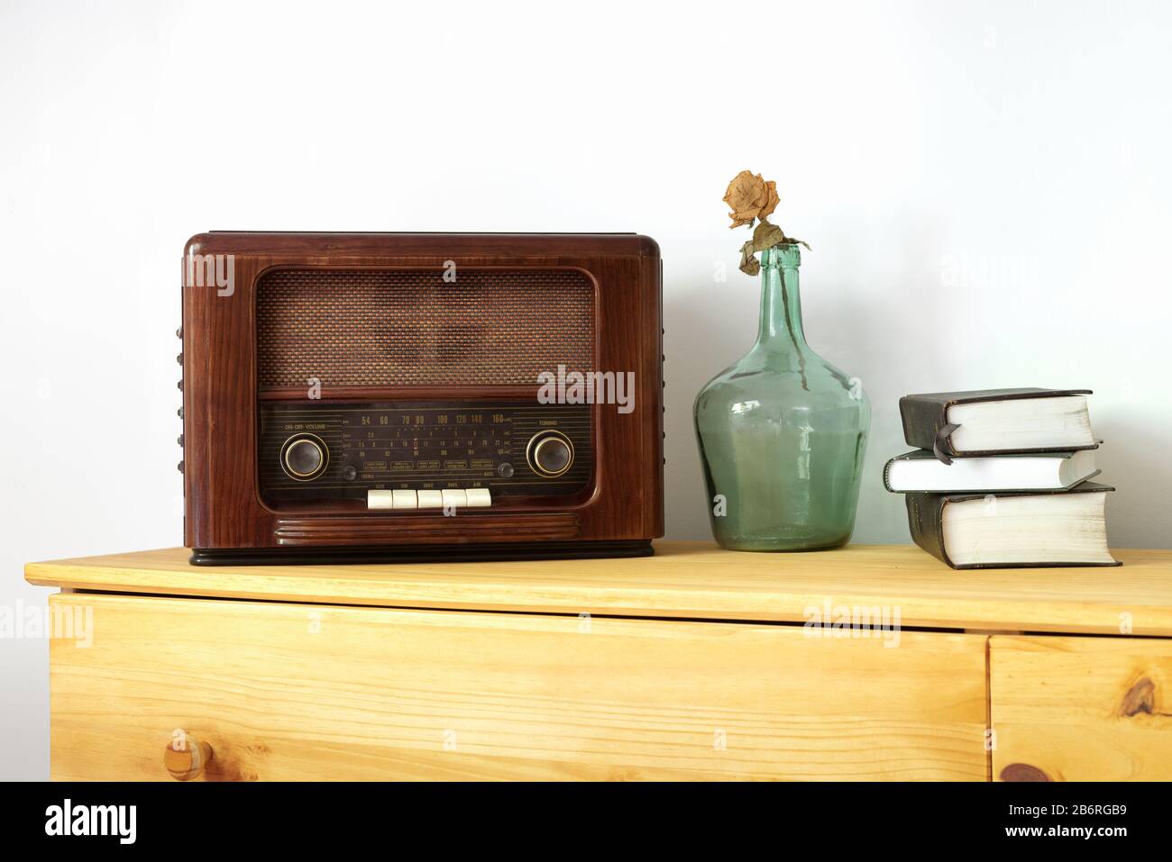 Vintage radio made of wood, green vase and old books on a table Stock Photo