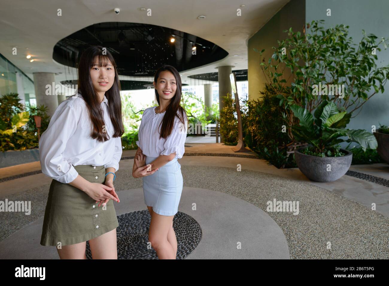 Two happy young beautiful Asian teenage girls together at the indoor garden Stock Photo