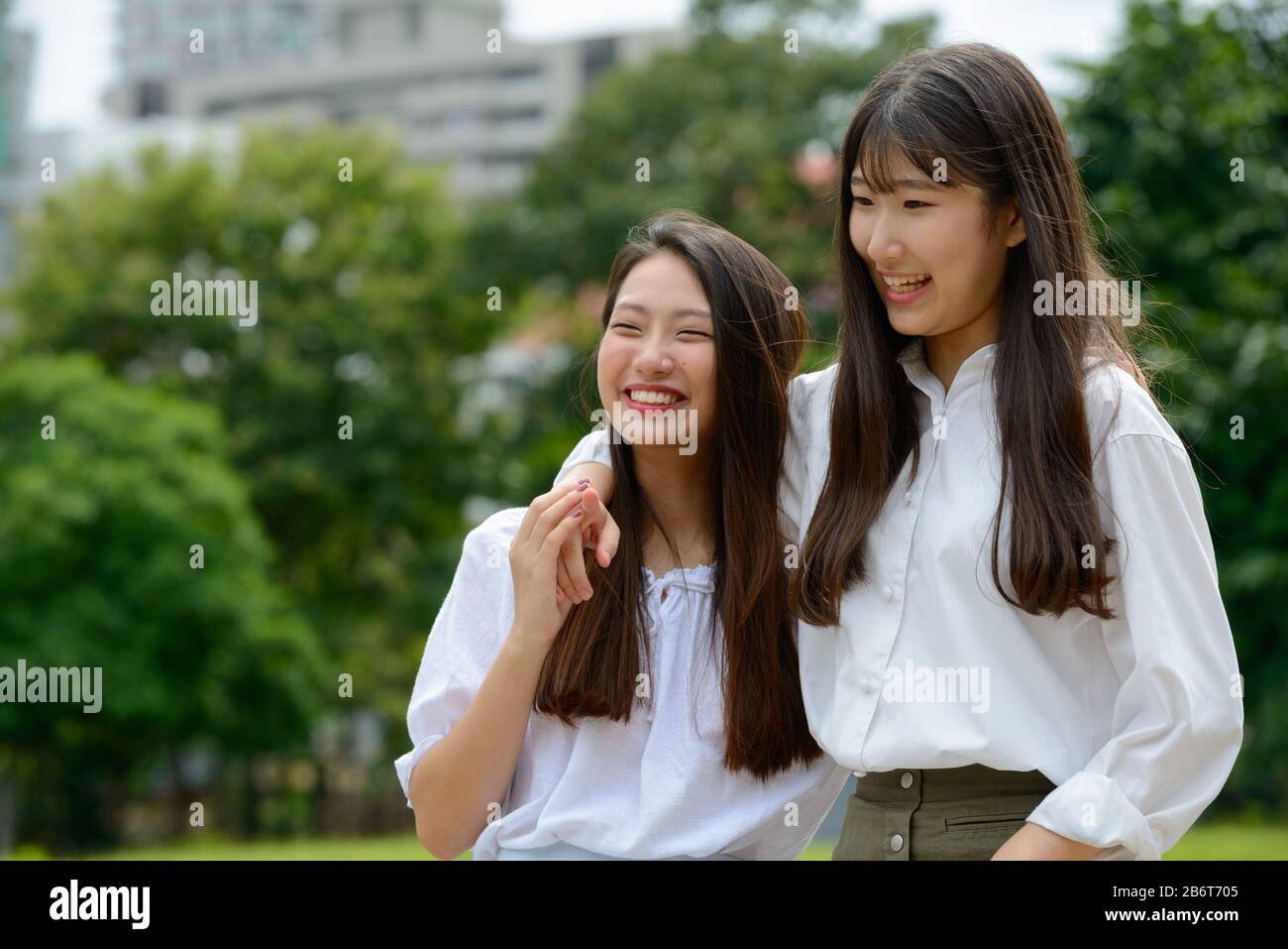 Two happy young beautiful Asian teenage girls bonding together at the park Stock Photo