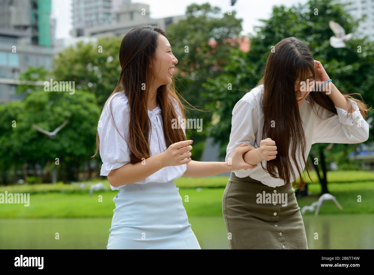 Two happy young beautiful Asian teenage girls having fun together at the park Stock Photo