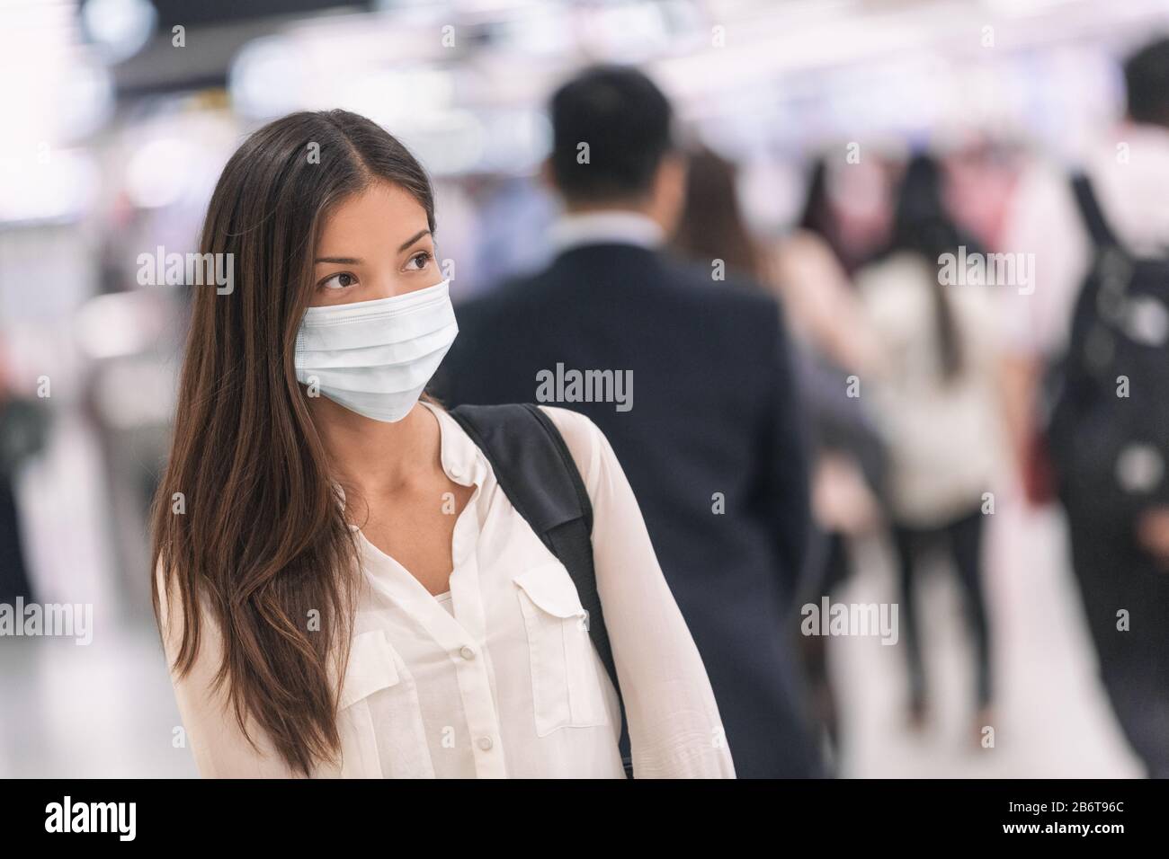 Virus mask Asian woman travel wearing face protection in prevention for coronavirus in China. Lady walking in public space bus station or airport. Stock Photo