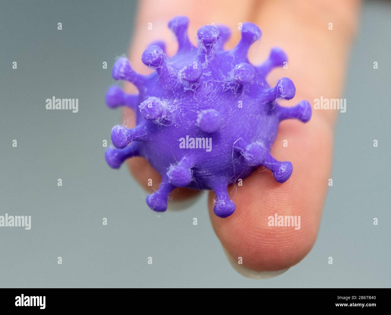 Dresden, Germany. 11th Mar, 2020. A medical-technical assistant in the laboratory of the TU Institute for Medical Microbiology, Hygiene and Virology at the University Hospital of Dresden holds a 3D print of a corona virus on two fingers. Credit: Robert Michael/dpa-Zentralbild/dpa/Alamy Live News Stock Photo