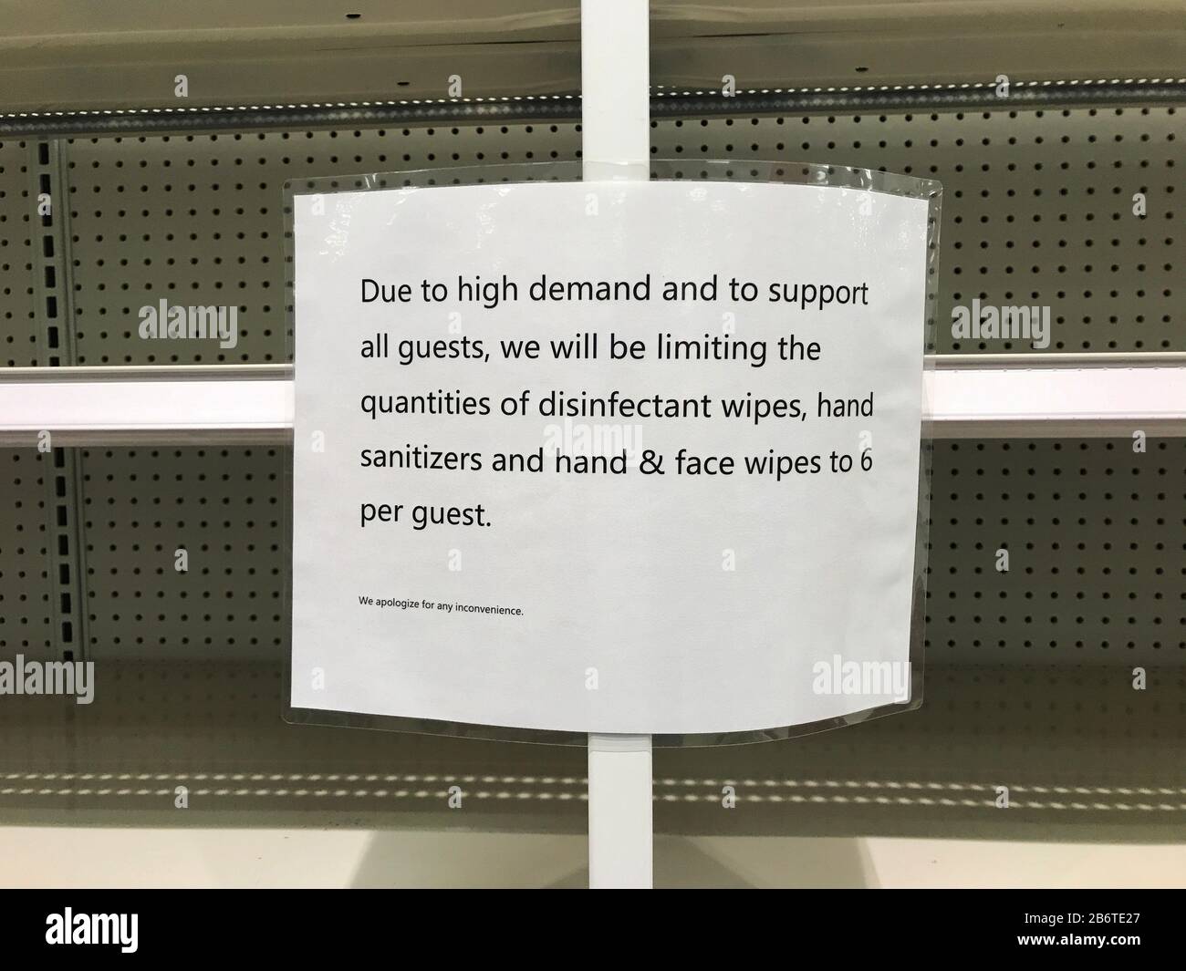 Empty shelves in supermarket with sign informing customers store places purchasing limits on some products as people fear the coronavirus outbreak Stock Photo