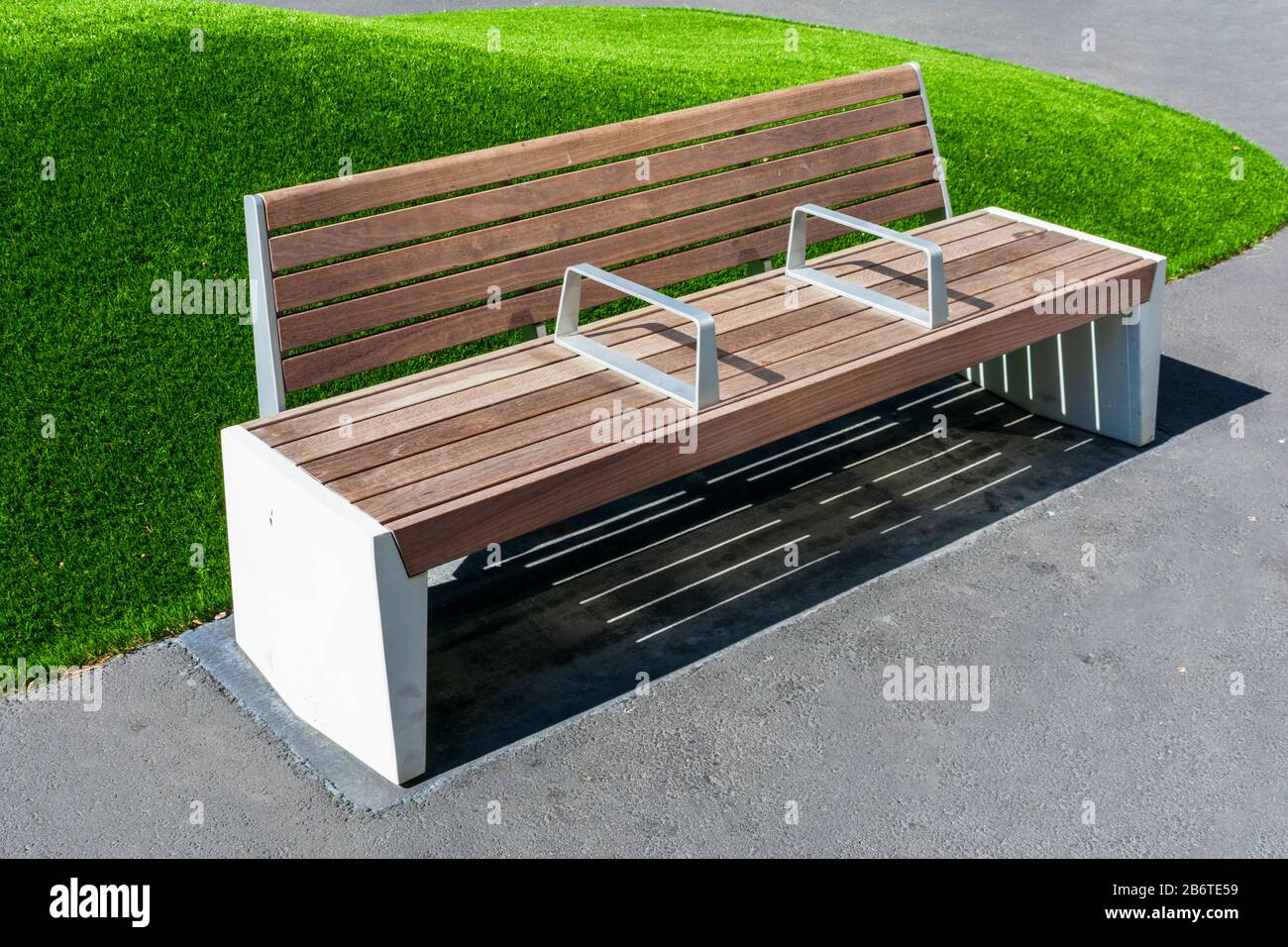 Empty bench with armrest in the middle to prevent people from sleeping, resting or lying down on the bench in the park. Stock Photo
