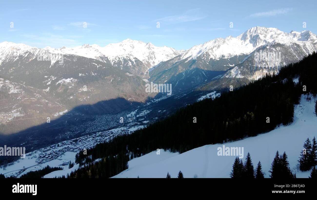 Aerial winter scene of alpine snowy mountain peaks and dark spruce forest in snow Stock Photo