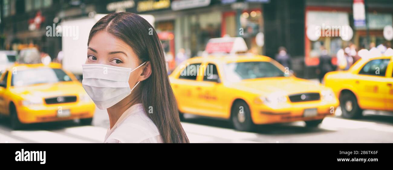 Corona virus travel ban China woman tourist walking in New York city street wearing surgical mask coronavirus protection, outbreak spreading scare. Panoramic banner background of traffic taxi cabs. Stock Photo