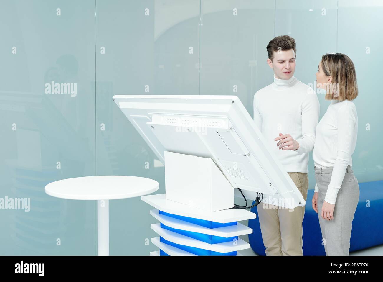 Young man using modern interactive display while discussing project with colleague in office Stock Photo