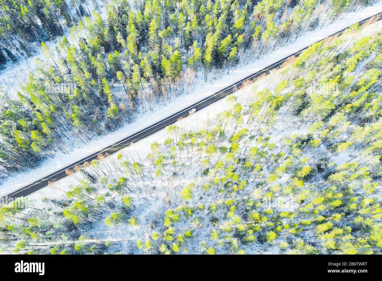 Aerial view of a winter country road in the forest with moving cars ...