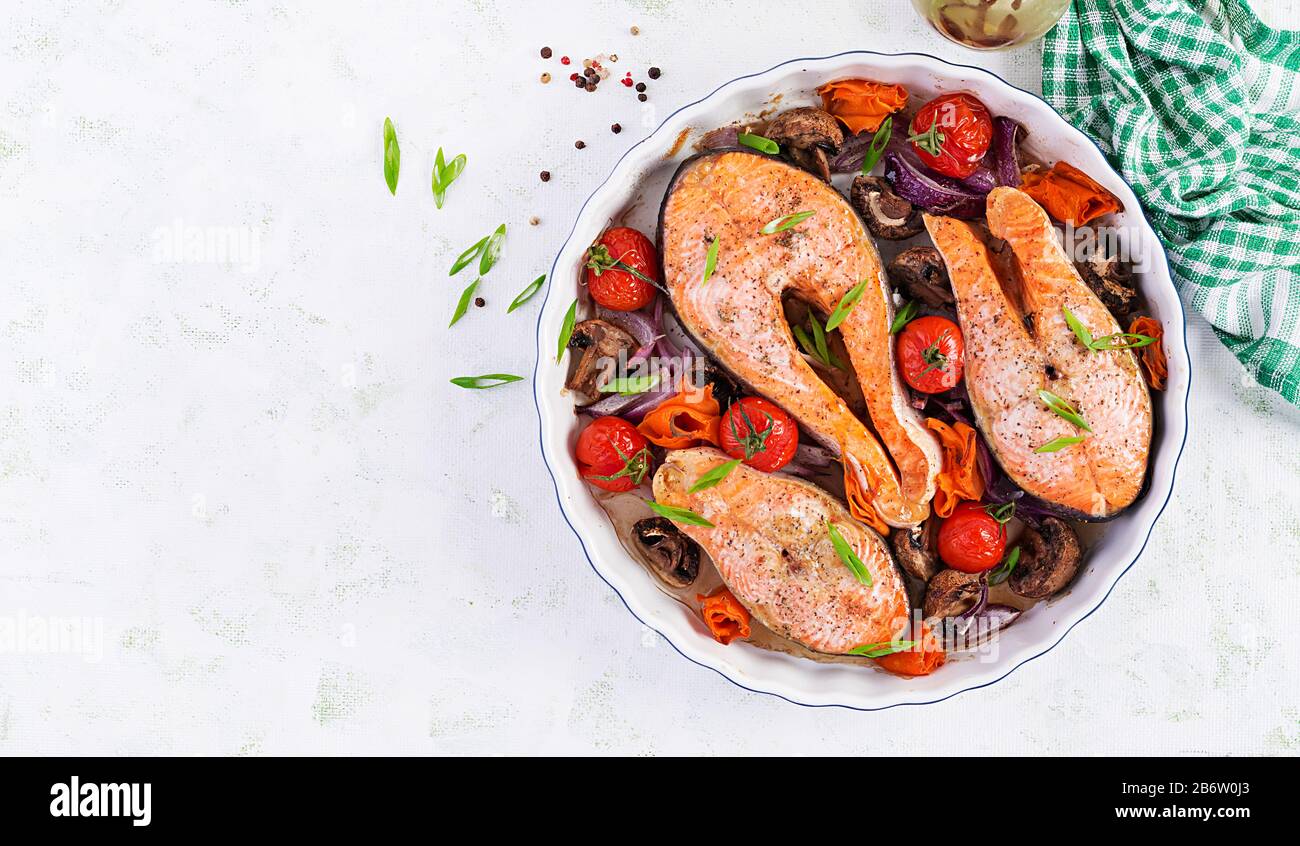 Ketogenic dinner. Baked salmon fish steak with tomatoes, mushrooms and
