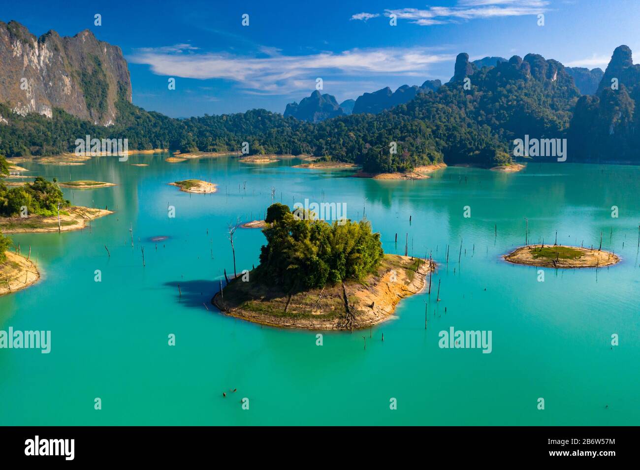Aerial drone view looking down onto tiny, jungle covered islands in a huge lake surrounded by limestone cliffs. (Cheow Lan Lake, Khao Sok) Stock Photo