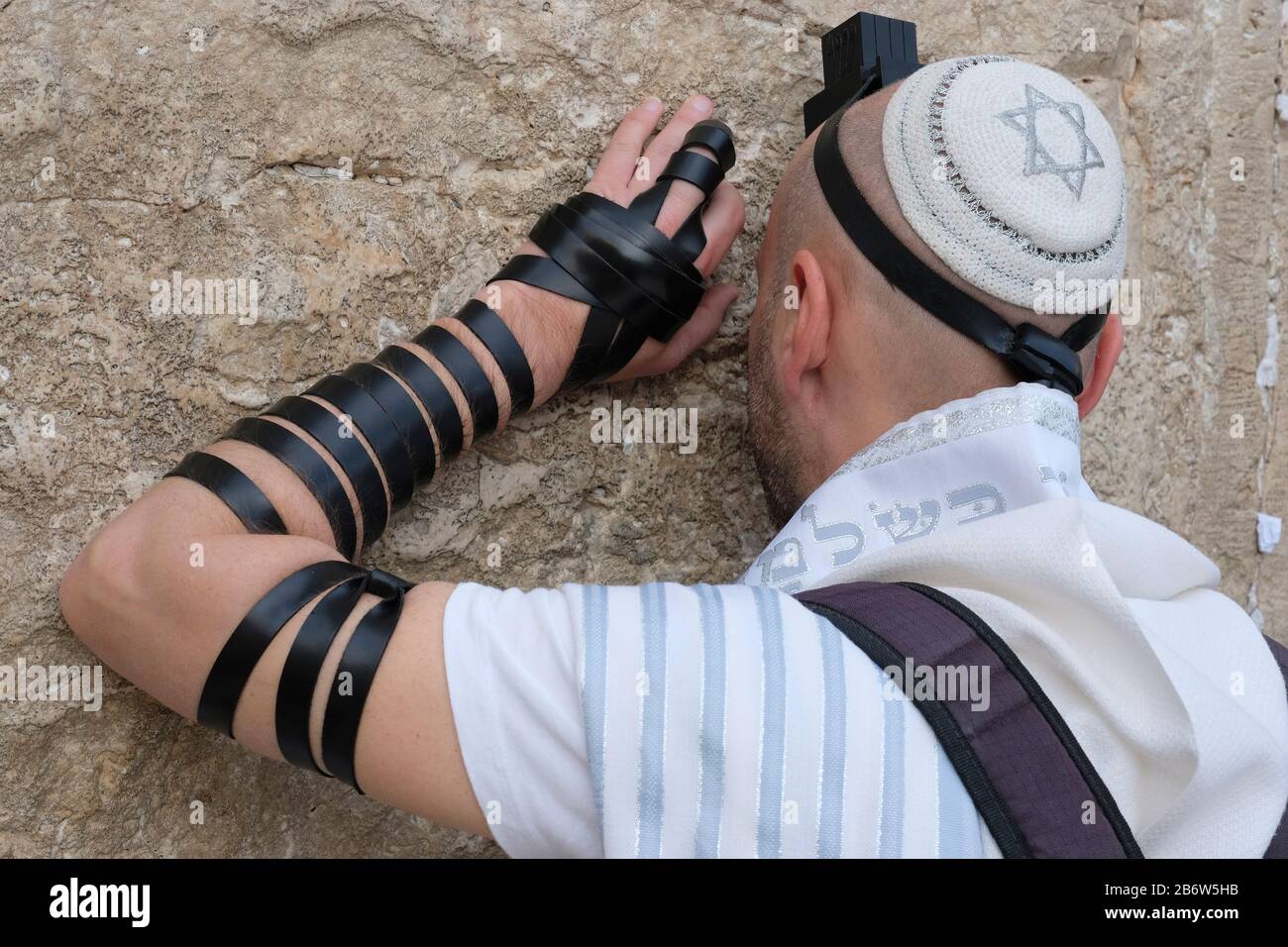 Orthodox Jewish man with tefillin and tallit, sitting alone and