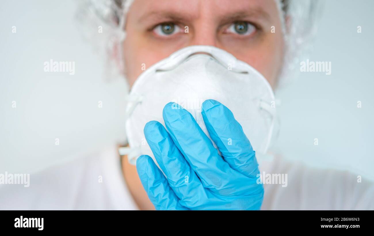 Hands with blue gloves puts on respiratory mask. Concept of against transmissible infectious diseases and as protection the flu. Coronavirus 2019-nCoV Stock Photo