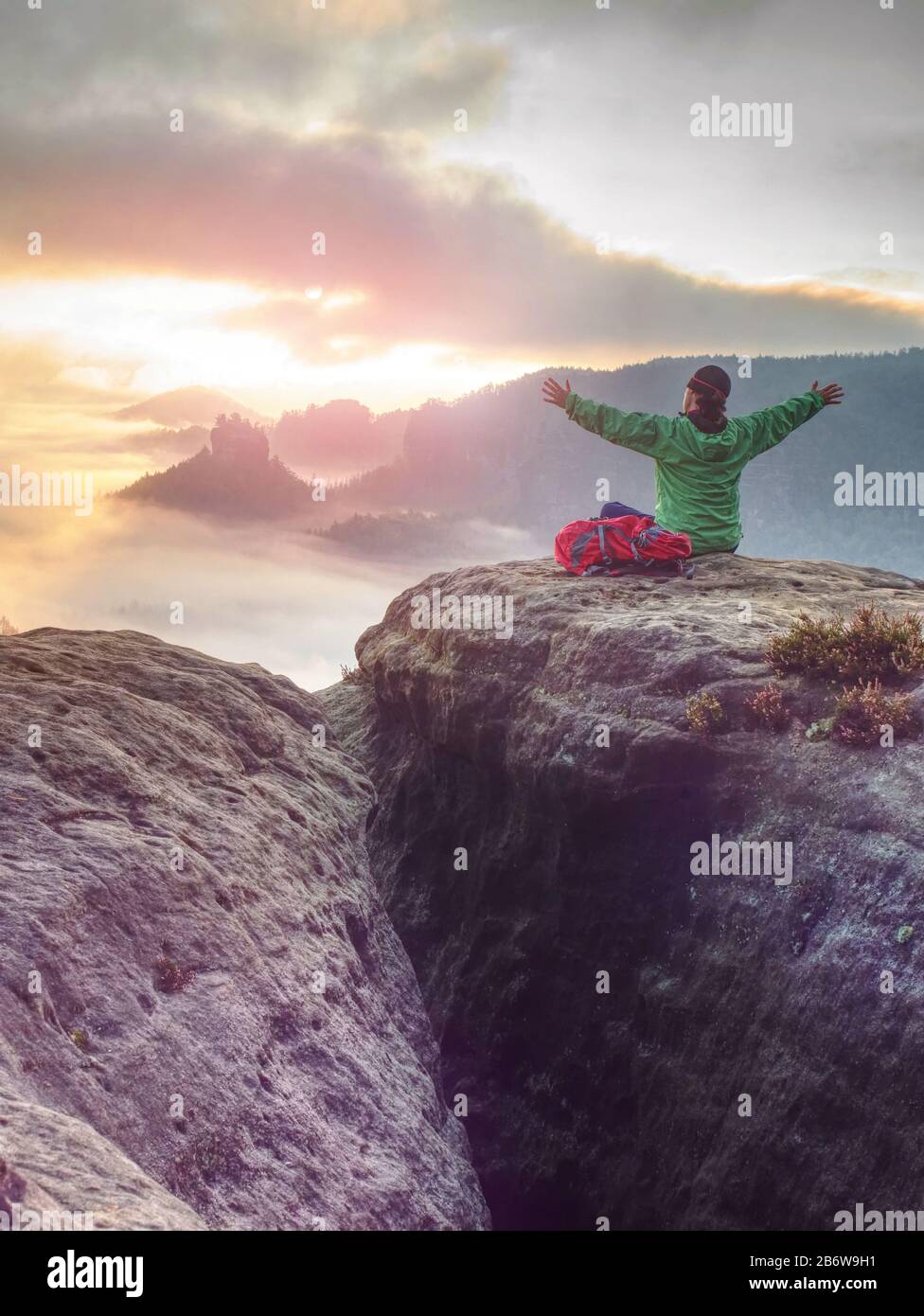 Girl on mountain summit hands raised over clouds. Travel Lifestyle success concept adventure active vacations outdoor Stock Photo